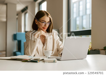 A Professional Woman Actively Engaged in Working on Her Laptop in a Modern Office Environment A Professional Woman Actively Engaged in Working on Her Laptop in a Modern Office Environment 129549701