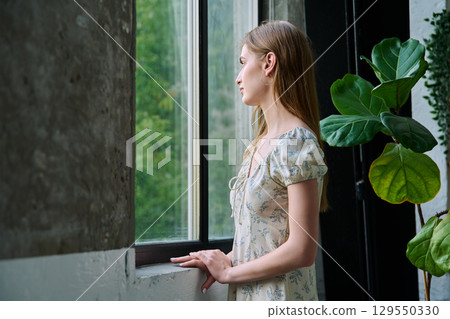 Young beautiful dreaming romantic girl looking out the window Young beautiful dreaming romantic girl looking out the window 129550330