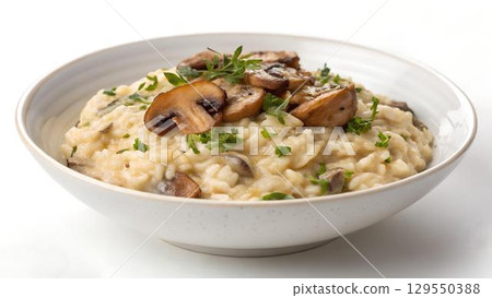 The image showcases a creamy mushroom risotto served in a modern white bowl, garnished with fresh 129550388
