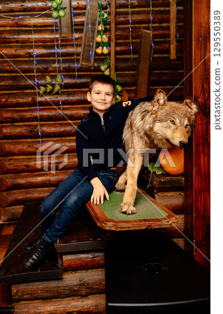 Boy posing with stuffed wolf in wooden house 129550389