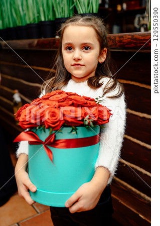 Girl holding red roses bouquet in light blue round gift box Girl holding red roses bouquet in light blue round gift box 129550390