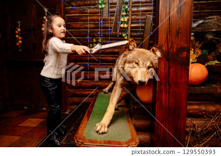 Little girl playing with toy sword near stuffed wolf in rustic decor Little girl playing with toy sword near stuffed wolf in rustic decor 129550393
