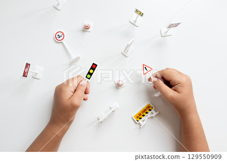 Child hands holding miniature traffic signs on white background Child hands holding miniature traffic signs on white background 129550909
