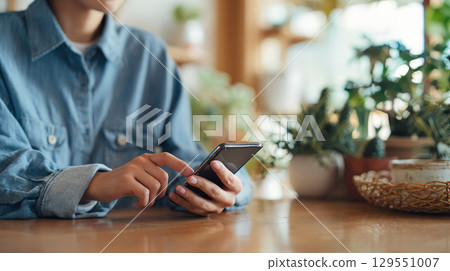 Woman's hand operating a smartphone in the living room 01 129551007