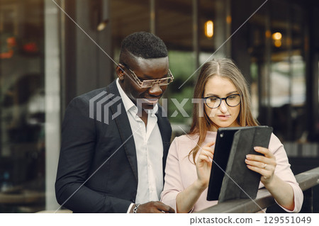 African man. Guy in a black suit. Students with a talet. Girl in white blouse. International people in a cafe. 129551049