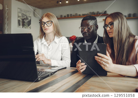African man. Guy in a black suit. Students with a laptop. Girl in white blouse. International people in a cafe. 129551058