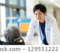 Male doctor talking to an elderly person in a wheelchair 129551222