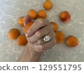 Apricots on gray stone with woman's hand and oval diamond ring 129551795