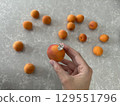 Hand holding apricot with oval diamond engagement ring 129551796