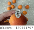 Diamond engagement ring placed on top of fresh apricot 129551797