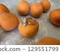 Oval diamond engagement ring surrounded by fresh apricots 129551799