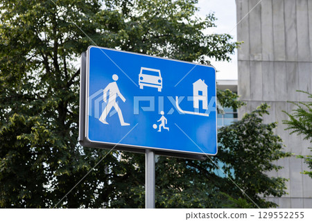 Blue traffic sign with white pictograms illustrating a pedestrian, car, playing child, and house, indicating a safe, quiet residential zone for shared community living Blue traffic sign with white pictograms illustrating a pedestrian, car, playing child, and house, indicating a safe, quiet residential zone for shared community living 129552255