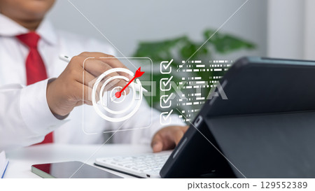 Business strategy, goal setting, marketing objectives, and achieving success in a professional environment.Businessman uses stylus on digital screen with target and goals list. Business strategy, goal setting, marketing objectives, and achieving success in a professional environment.Businessman uses stylus on digital screen with target and goals list. 129552389