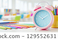 Back to school concept. Colorful pencils and alarm clock on table in classroom. 129552631