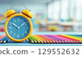 Back to school concept. Colorful pencils and alarm clock on table in classroom. 129552632