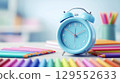 Back to school concept. Colorful pencils and alarm clock on table in classroom. 129552633