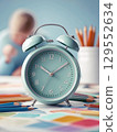 Back to school concept. Colorful pencils and alarm clock on table in classroom. 129552634