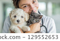 Cute kitten and puppy in the arms of a female veterinarian, in a veterinary clinic. Concept of advertising veterinary services and pet care.  129552653