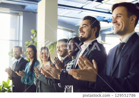 A diverse and enthusiastic audience is applauding the speaker, smiling with joy. 129552786
