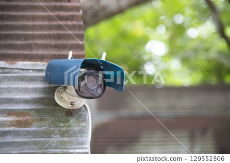 Old CCTV camera with oil can roof mounted on rusty wall Old CCTV camera with oil can roof mounted on rusty wall 129552806
