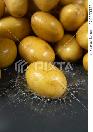 Whole fresh unpeeled potatoes in a splash of water. 129553332