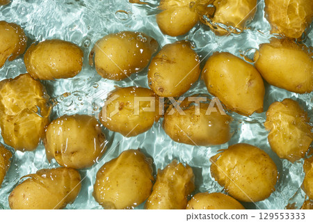Whole Organic Raw Potatoes In Water Top View, Splash And Ripples. Whole Organic Raw Potatoes In Water Top View, Splash And Ripples. 129553333