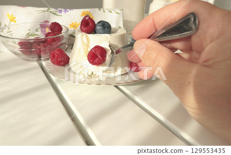 Woman and ricotta cheese dessert with berries. Table setting. Raspberries and blueberries. Healthy eating and vitamins. Environmentally friendly products. Mediterranean diet. Woman and ricotta cheese dessert with berries. Table setting. Raspberries and blueberries. Healthy eating and vitamins. Environmentally friendly products. Mediterranean diet. 129553435