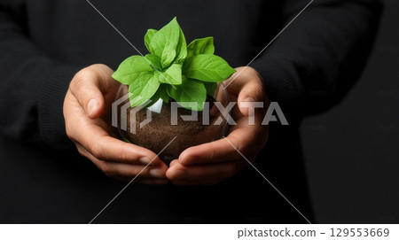 Hands Holding a Glass Globe Containing a Small Plant, Symbolizing Growth and Environmental Care 129553669