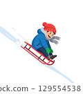 Joyful child sledding downhill in winter attire with red hat and scarf 129554538