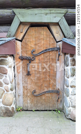 Rustic wooden door with iron hardware and stone surround in architectural setting Rustic wooden door with iron hardware and stone surround in architectural setting 129554554