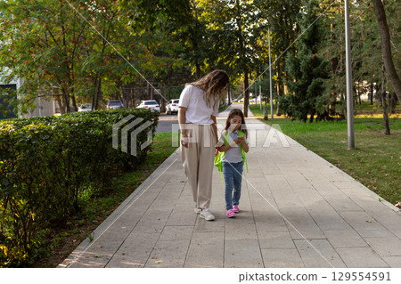 Mother and daughter strolling in park on a sunny day Mother and daughter strolling in park on a sunny day 129554591