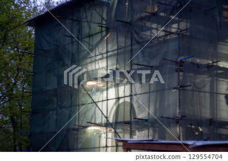 Building under renovation with green safety netting during daytime 129554704