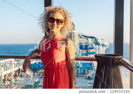 Beautiful happy woman on cruise ship deck. Elegant lady in red dress relaxing on vacation. Sea travel and summer holiday. High quality photo Beautiful happy woman on cruise ship deck. Elegant lady in red dress relaxing on vacation. Sea travel and summer holiday. High quality photo 129555183