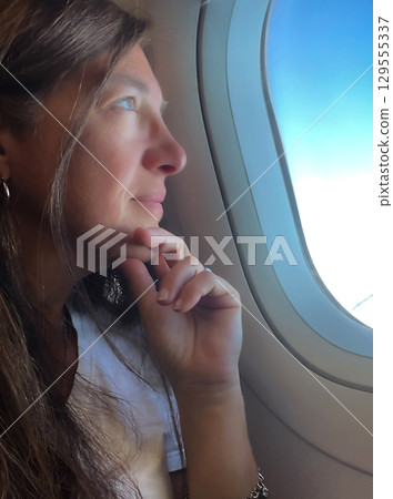 Young woman enjoying the view from the airplane window Young woman enjoying the view from the airplane window 129555337