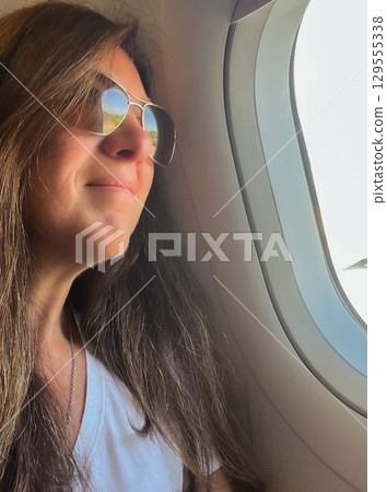 Relaxed and happy female traveler gazing at clouds and landscapes. Vertical shot Relaxed and happy female traveler gazing at clouds and landscapes. Vertical shot 129555338