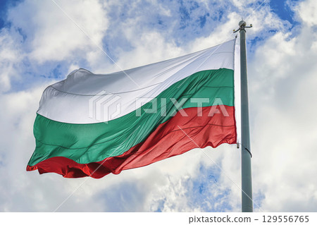 Bulgarian Flag on cloudy blue sky, background. National flag of Bulgaria waving in wind, symbolizing pride and independence. Concept of Bulgaria flag, patriotism, national identity, state symbol 129556765