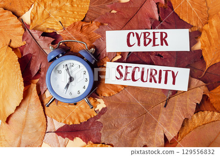Blue alarm clock is on top of a pile of orange leaves Blue alarm clock is on top of a pile of orange leaves 129556832