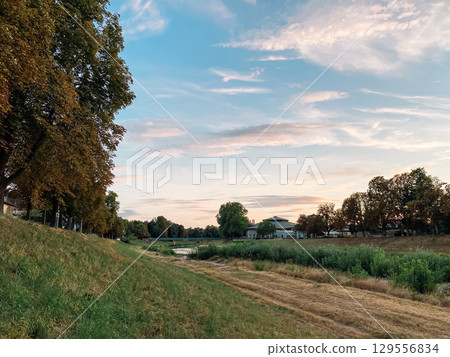 Beautiful, serene landscape with a large hill and a river Beautiful, serene landscape with a large hill and a river 129556834