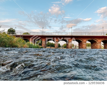 Bridge spans a river with a train passing underneath Bridge spans a river with a train passing underneath 129556836
