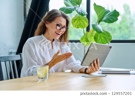 Middle aged female teacher entrepreneur using digital tablet for video online meeting Middle aged female teacher entrepreneur using digital tablet for video online meeting 129557201