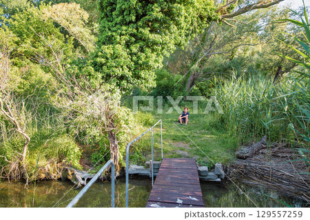 Wooden pier leading to green forest path 129557259