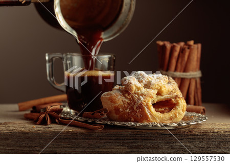 Viennese strudel and black coffee on an old wooden table. 129557530