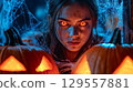 Spooky halloween scene with creepy glowing eyed character and pumpkins 129557881