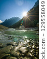 Summer landscape of the Amanauz mountain river, the sun peeking out from behind the mountains 129558049