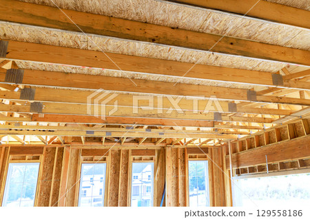 Construction underway in new residential building with exposed framing large windows creating natural light 129558186