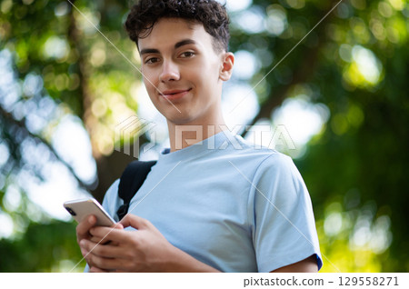 Sweet dark-haired teen with a phone in hands in the park Sweet dark-haired teen with a phone in hands in the park 129558271