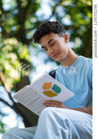 Dark-haired positive teen sitting on the steps in the park 129558298