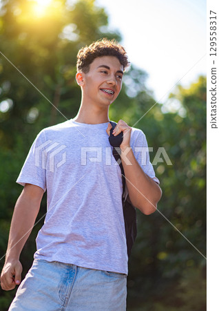 Contented teen with a backpack waling in the park 129558317