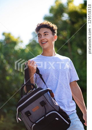 Contented teen with a backpack waling in the park Contented teen with a backpack waling in the park 129558318