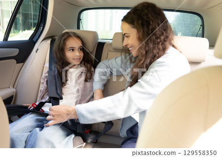 Mom and daughter spending time together and watching something while sitting in a car 129558350
